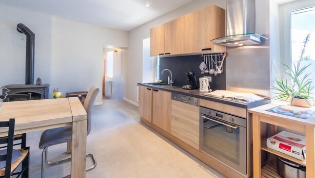 A modern kitchen with wooden cabinets, stainless steel appliances, and a dining area with a table and chairs. - ESCALE - LA MOTTE SERVOLEX (LA MOTTE SERVOLEX)