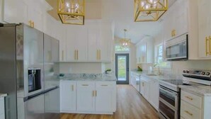 Una cocina moderna con armarios blancos, electrodomésticos de acero inoxidable y suelo de madera.