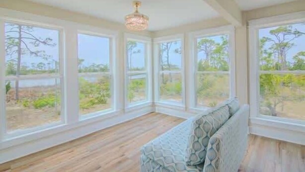 Una habitación con ventanas amplias, suelo de madera y un banco estampado.