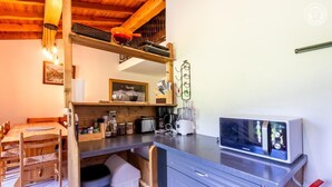 Una cocina compacta con microondas integrado, cafetera y refrigerador pequeño.