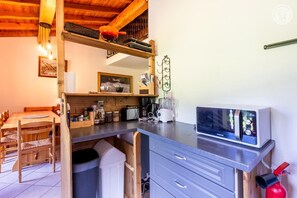 Una cocina compacta con microondas integrado, cafetera y refrigerador pequeño.