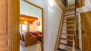 Un interior de madera con una escalera, un sofá y una zona de comedor.
