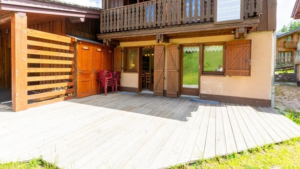En træbygning med balkon, overdækket indgang og træterrasse.