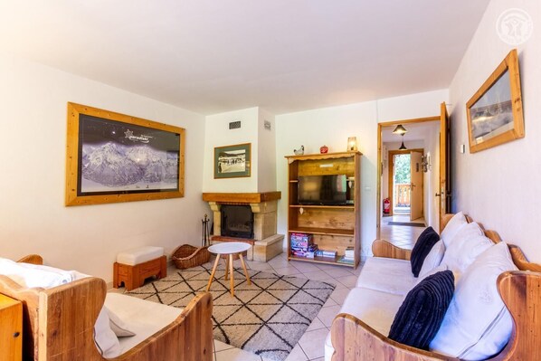 A cozy living room with a fireplace, wooden furniture, and a large framed picture on the wall. - PETIT REFUGE - LA PLAGNE TARENTAISE (LA PLAGNE TARENTAISE)