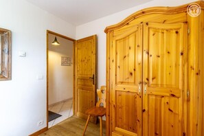 A room with wooden wardrobes, a chair, and a door leading to another room. - PETIT REFUGE - LA PLAGNE TARENTAISE (LA PLAGNE TARENTAISE)