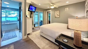 A hotel room with a large bed, a ceiling fan, a TV mounted on the wall, and a view of the outdoors. - ⭐NEW⭐ Stunning Beachfront Living w/ Gameroom & Firepit Near Acadia  (Gouldsboro)