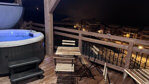 Una terraza de madera con un jacuzzi y sillas de madera.
