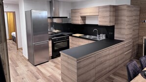 Una cocina moderna con un refrigerador de acero inoxidable, estufa negra y armarios de madera.