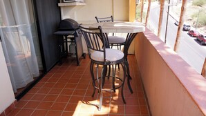 Ein Balkon mit Tisch, Stühlen, Grill und Blick auf eine Straße.