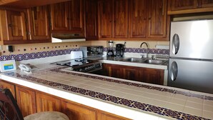 Eine Küche mit Holzschränken, einem Edelstahlkühlschrank, einer Spüle mit zwei Becken und einer Rückwand mit Muster.