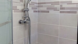 Een douchecabine met glazen wanden, een handdouche en een regendouche aan de muur.