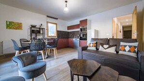 Ein modernes Wohnzimmer mit Sofa, Couchtisch und Essbereich mit Stühlen und Tisch.