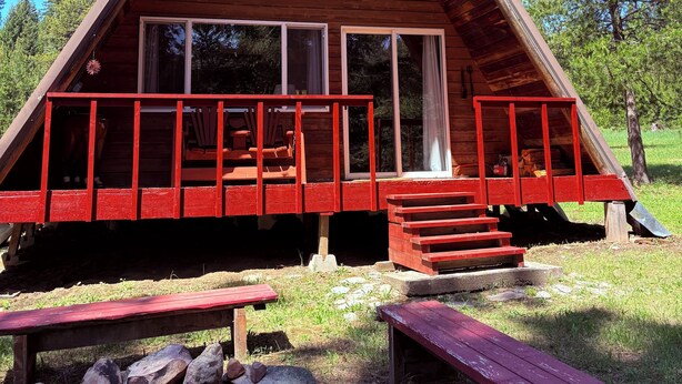 A wooden cabin with a triangular roof, large windows, and a porch with red railings. - A-frame cabin tucked in the woods with complete privacy in the mountains.   (De Borgia)