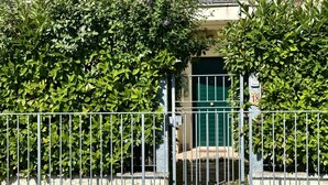 Uma entrada com portão e cerca de metal, uma porta verde e uma caixa de correio com o número 18.