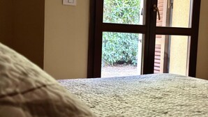 Um quarto com cama, janela e vista para o verde.
