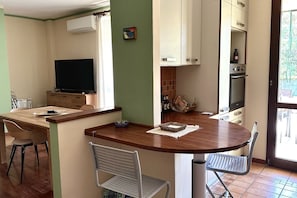A compact kitchen with a dining area, a flat-screen TV, and a large window. - N293 - Sirolo, comfortable three-room apartment in a quiet area (Sirolo)