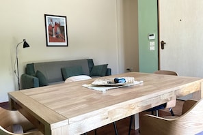 A room with a wooden dining table, a green sofa, a framed picture on the wall, and a door with a lock. - N293 - Sirolo, comfortable three-room apartment in a quiet area (Sirolo)