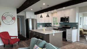 A modern kitchen with white cabinets, stainless steel appliances, and a central island. - Notre Dame Football! 4-bedroom cottage on Diamond Lake! (Cassopolis)