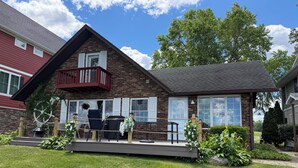 A two-story house with a balcony, a deck, and a patio area with outdoor furniture. - Notre Dame Football! 4-bedroom cottage on Diamond Lake! (Cassopolis)