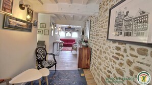 A cozy interior with a wooden ceiling, stone wall, and a framed black and white drawing. - La Maison Gousset - GUINGAMP (GUINGAMP)
