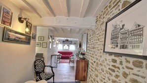 Un intérieur chaleureux avec un plafond en bois, un mur en pierre et un dessin en noir et blanc encadré.
