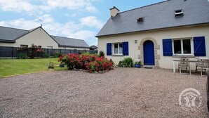 A house with a gravel driveway, a front garden with red flowers, and a blue door. - Les 2 Pointes - PLOUEZEC (PLOUEZEC)