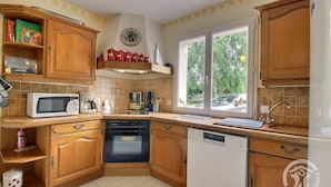 A compact kitchen with wooden cabinets, a microwave, a coffee maker, a toaster, and a dishwasher. - Les 2 Pointes - PLOUEZEC (PLOUEZEC)