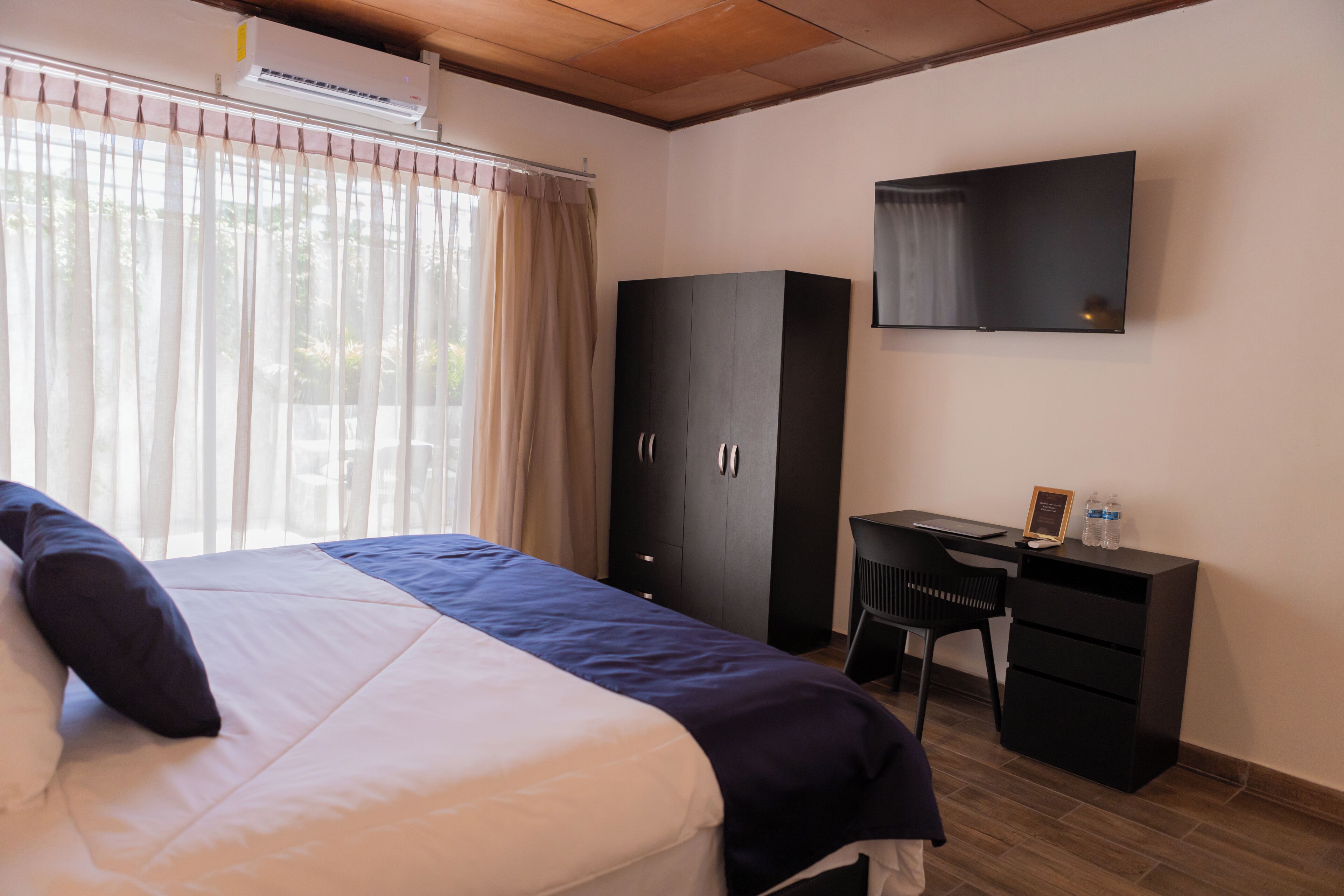 Een hotelkamer met een bed, een bureau, een kledingkast en een televisie.