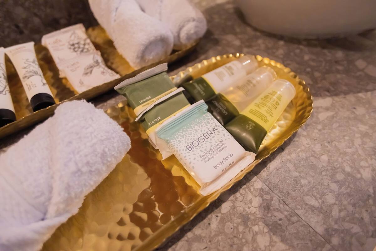 A tray with toiletries including Biogena body soap, a green bottle, and a white bottle on a marble countertop.