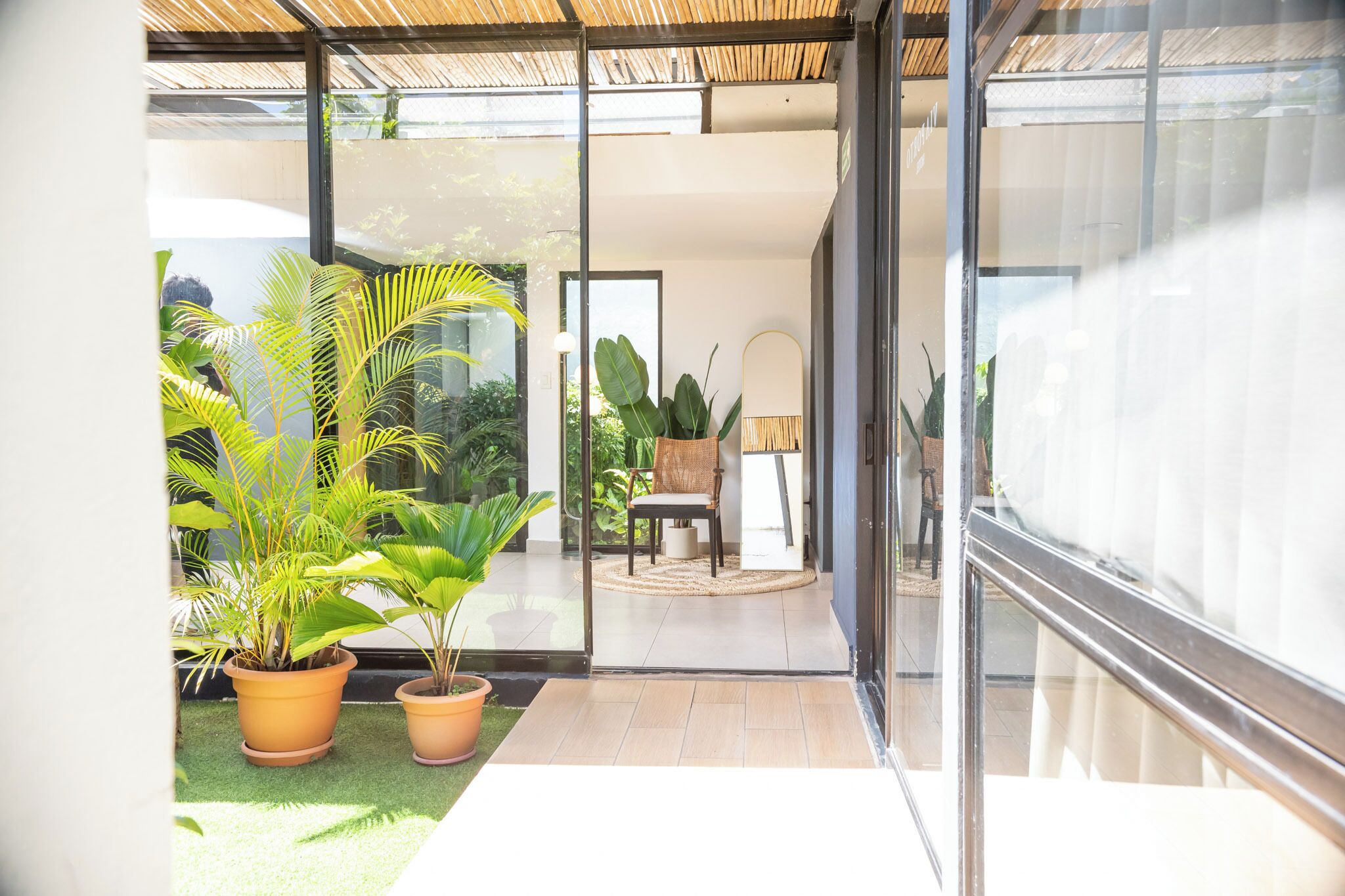 A modern interior with a glass door leading to a balcony with potted plants and a seating area.