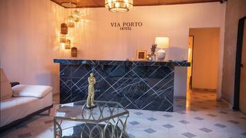 A reception area with a black marble counter, a gold statue, and a chandelier.