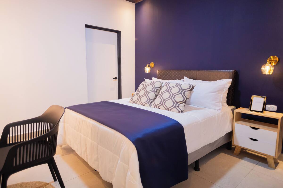 A neatly arranged bedroom with a bed, bedside tables, a chair, and a door.