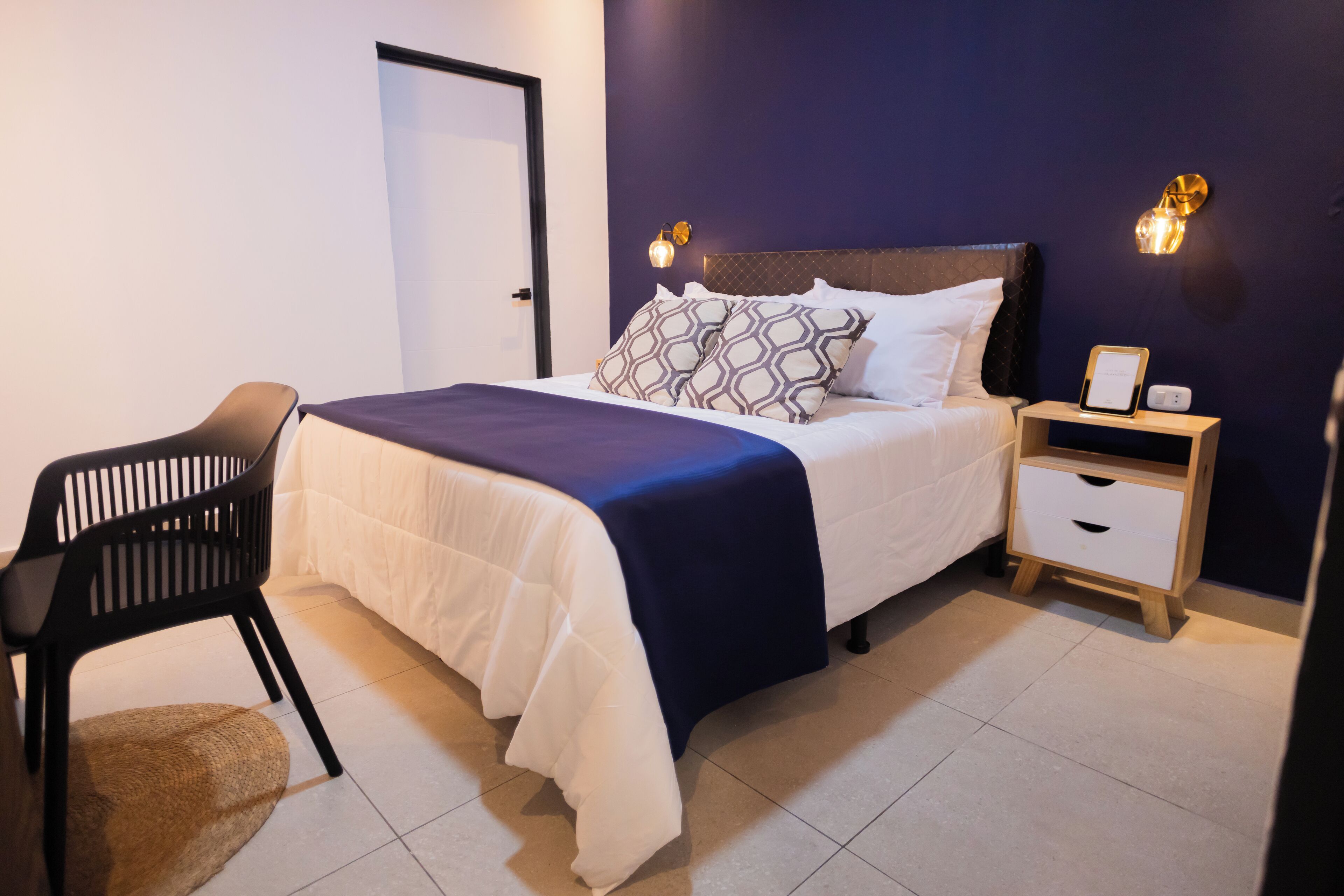 A neatly arranged bedroom with a bed, bedside tables, a chair, and a nightstand.
