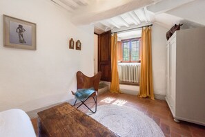 A room with a wooden chair, a white radiator, a wooden door, and a white cabinet. - Villa Poggio la Croce by MMega (Radda in Chianti)