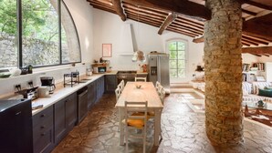 Una cocina rústica con suelo de piedra, una mesa de madera y un pilar de piedra.