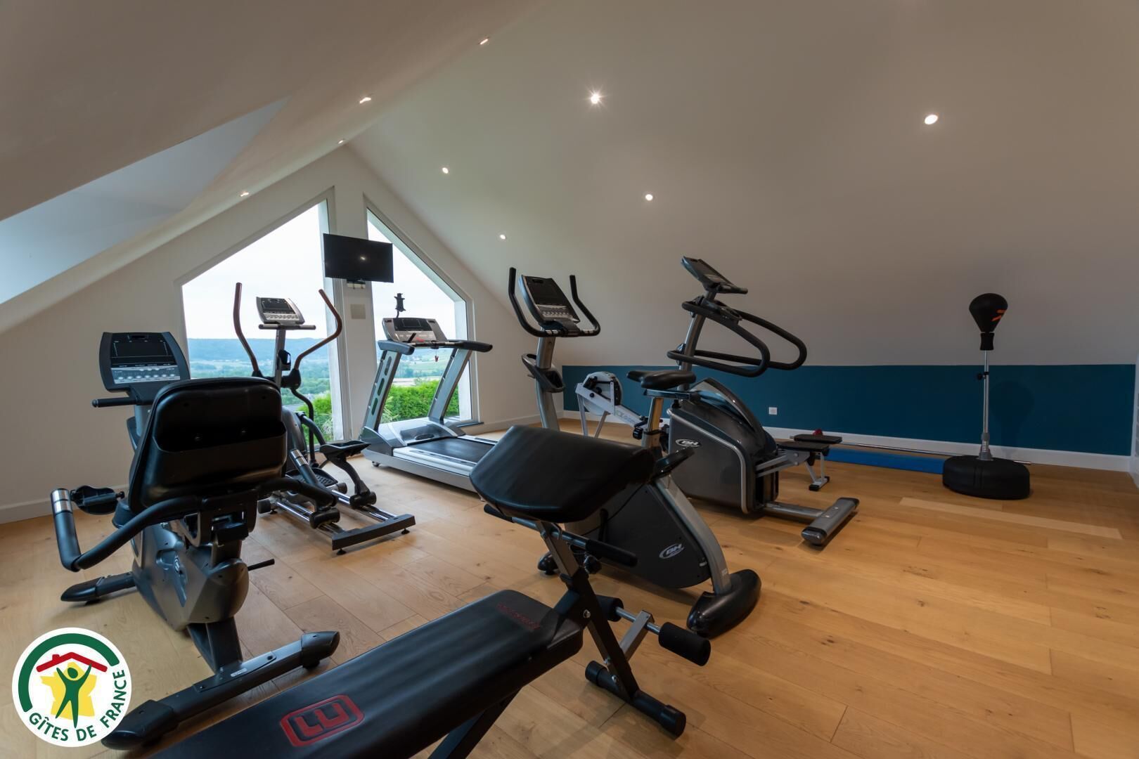 Una palestra con diverse attrezzature per esercizi, ampie finestre e vista sull'esterno.