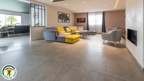 Una sala de estar moderna con un sofá gris, cojines amarillos, un sillón gris y un televisor montado en la pared.