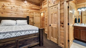 Un dormitorio con cama de madera, un armario grande y un baño con espejo y lavamanos.