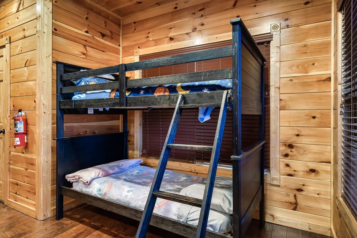 Een stapelbed met een ladder, houten wanden en een brandblusser.