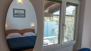 Ett sovrum med en säng, utsikt över en swimmingpool och en inramad tavla på väggen.