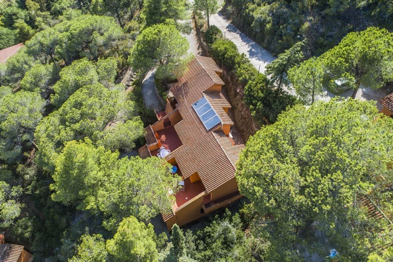 A house surrounded by dense trees with a sloped roof and solar panels.