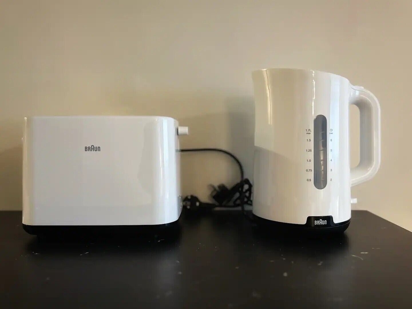 Un grille-pain Braun blanc et une bouilloire électrique Braun blanche, tous deux posés sur une surface noire.