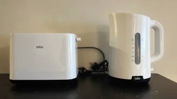 Un grille-pain Braun blanc et une bouilloire électrique Braun blanche, tous deux posés sur une surface noire.