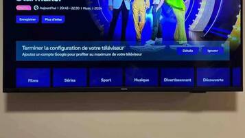 Ein Fernsehbildschirm zeigt eine Fernsehsender-Menüoberfläche mit Optionen wie Startseite, Entdecken, Live-TV und mehr.