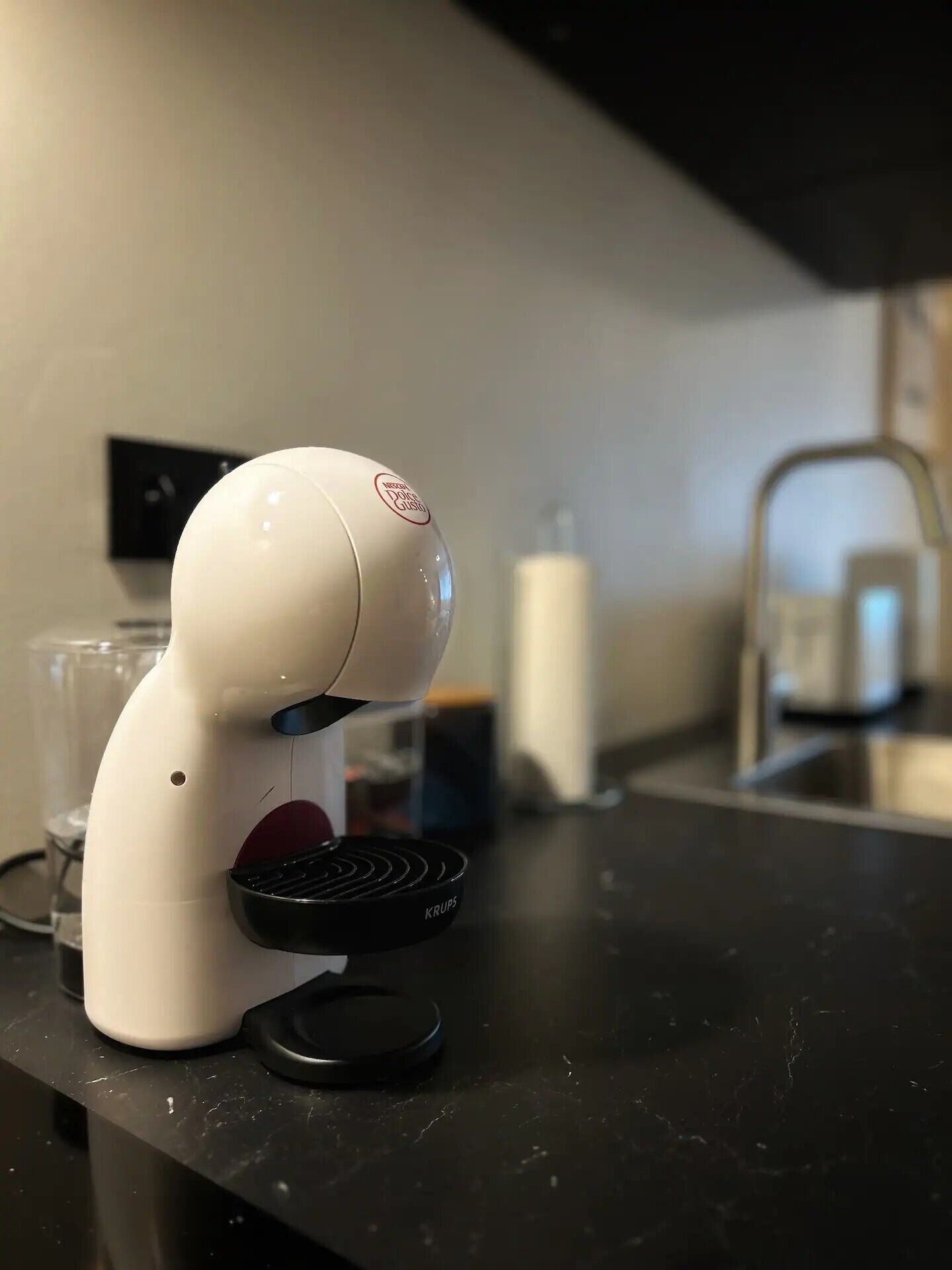 Een keuken met een witte koffieapparaat op het aanrecht.