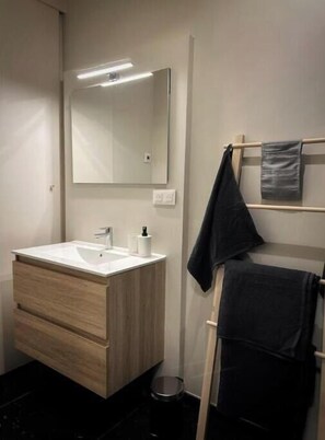 Une salle de bain moderne avec un meuble-lavabo en bois, un grand miroir et un porte-serviettes.
