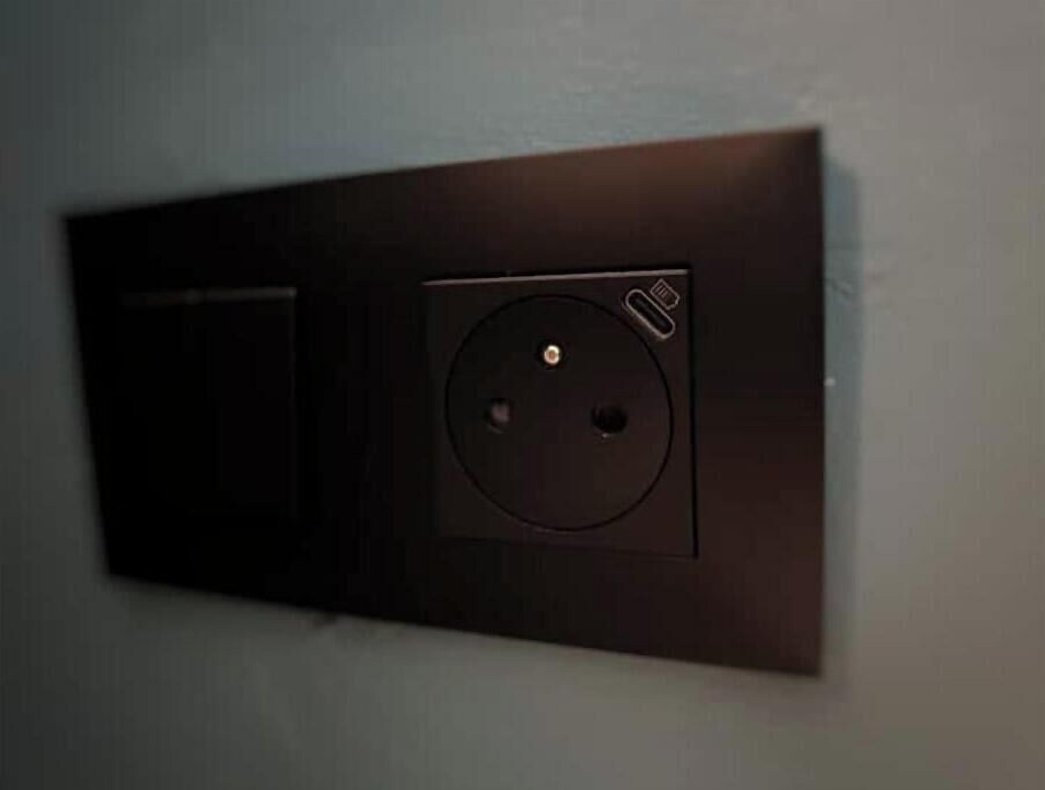 A wall-mounted electrical outlet with a circular cover and a USB port.