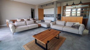 Un salon moderne avec un grand canapé d’angle, une table basse en bois et un coin repas comprenant une table et des chaises.