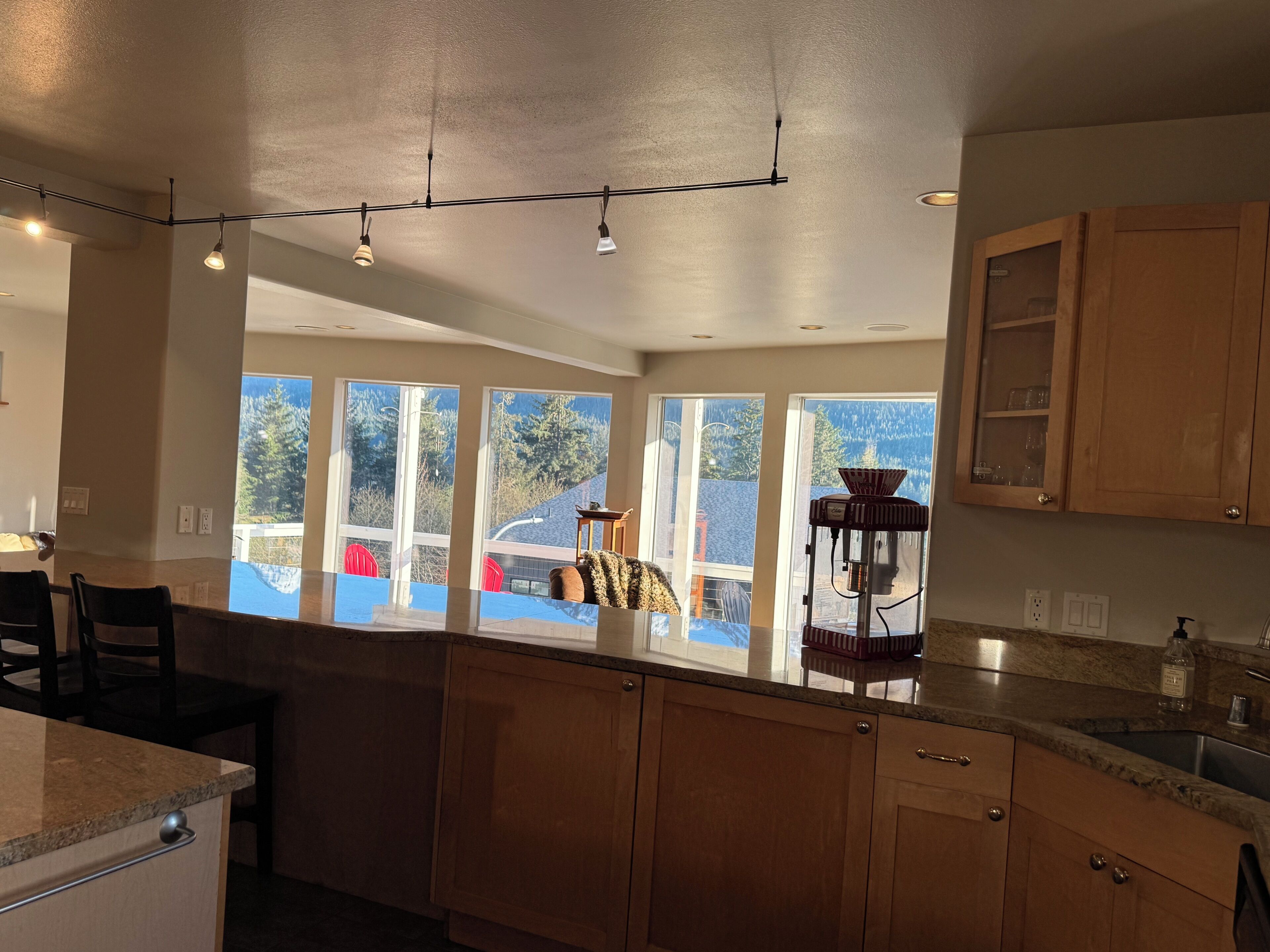 A kitchen with wooden cabinets, a granite countertop, and a view of a deck with outdoor furniture.