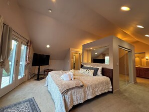 Ein Schlafzimmer mit einem großen Bett, einem Fernseher und einer Schiebetür zu einem Badezimmer.